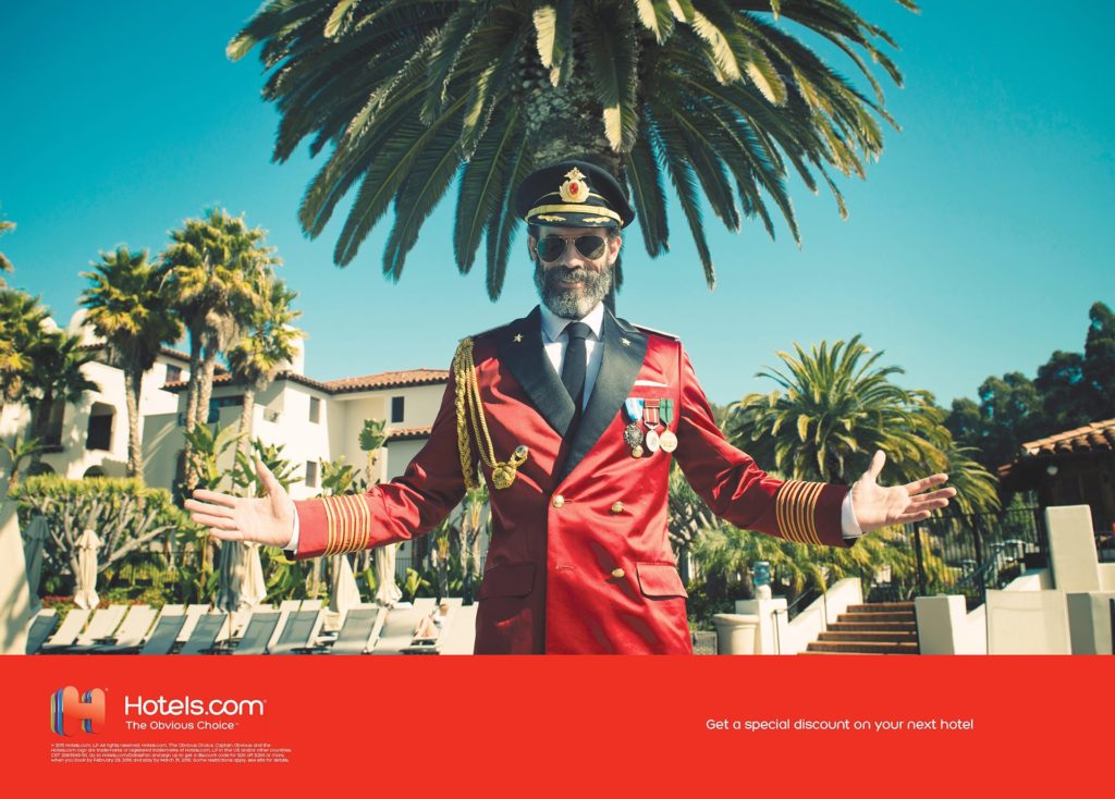 Funny advertisement of Captain Obvious proudly standing in front of a tropical destination with his arms open while earing his captain suit and hat. The funny still photography was used in a print ad for Hotels.com The Obvious Choice campaign photographed by The Wade Brothers and retouched by Realfake.