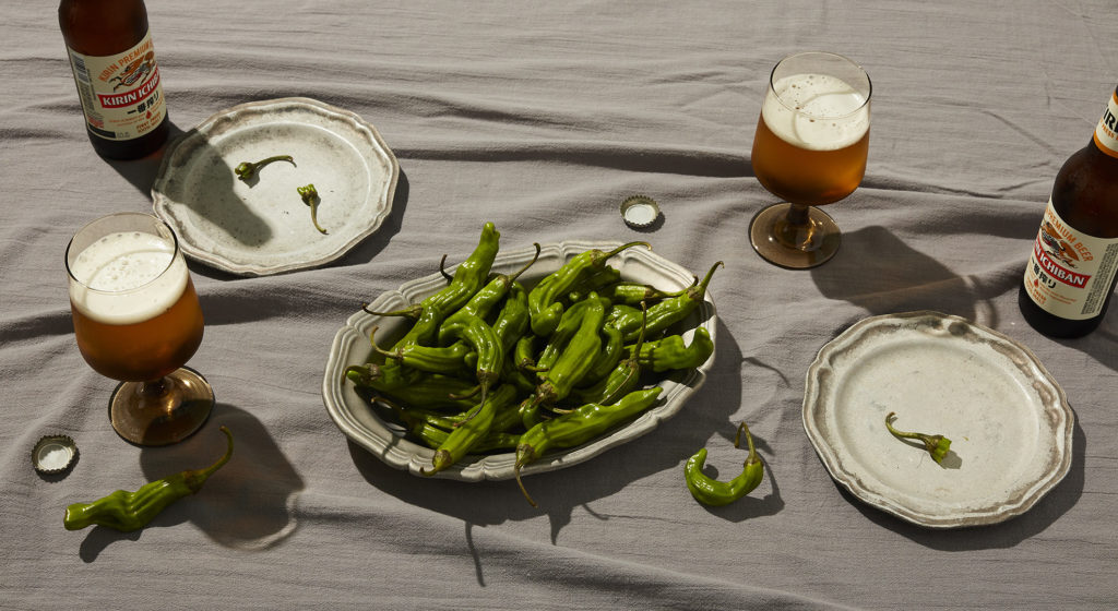 Commissionable artist Matt Mooney does food photography with shishito peppers and Kirin beer in tulip glassware on tabletop.
