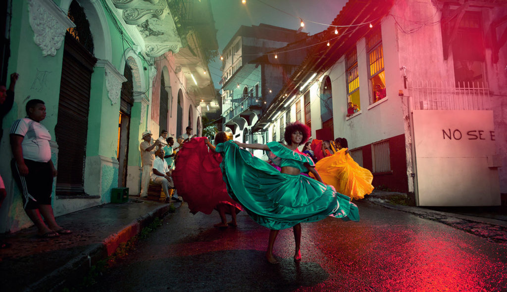 In Central America, dancers with colorful dresses dance in the street to local musicians, photographed by The Wade Brothers.