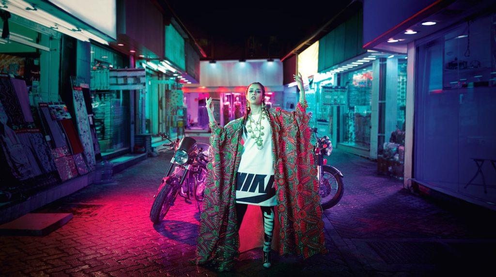 Female athlete standing in Middle Eastern street with neon lights photographed by commissionable artists, The Wade Brothers.